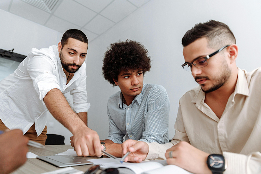 Three apparel manufacturing professionals discussing design and production plans at a table in a modern office setting.